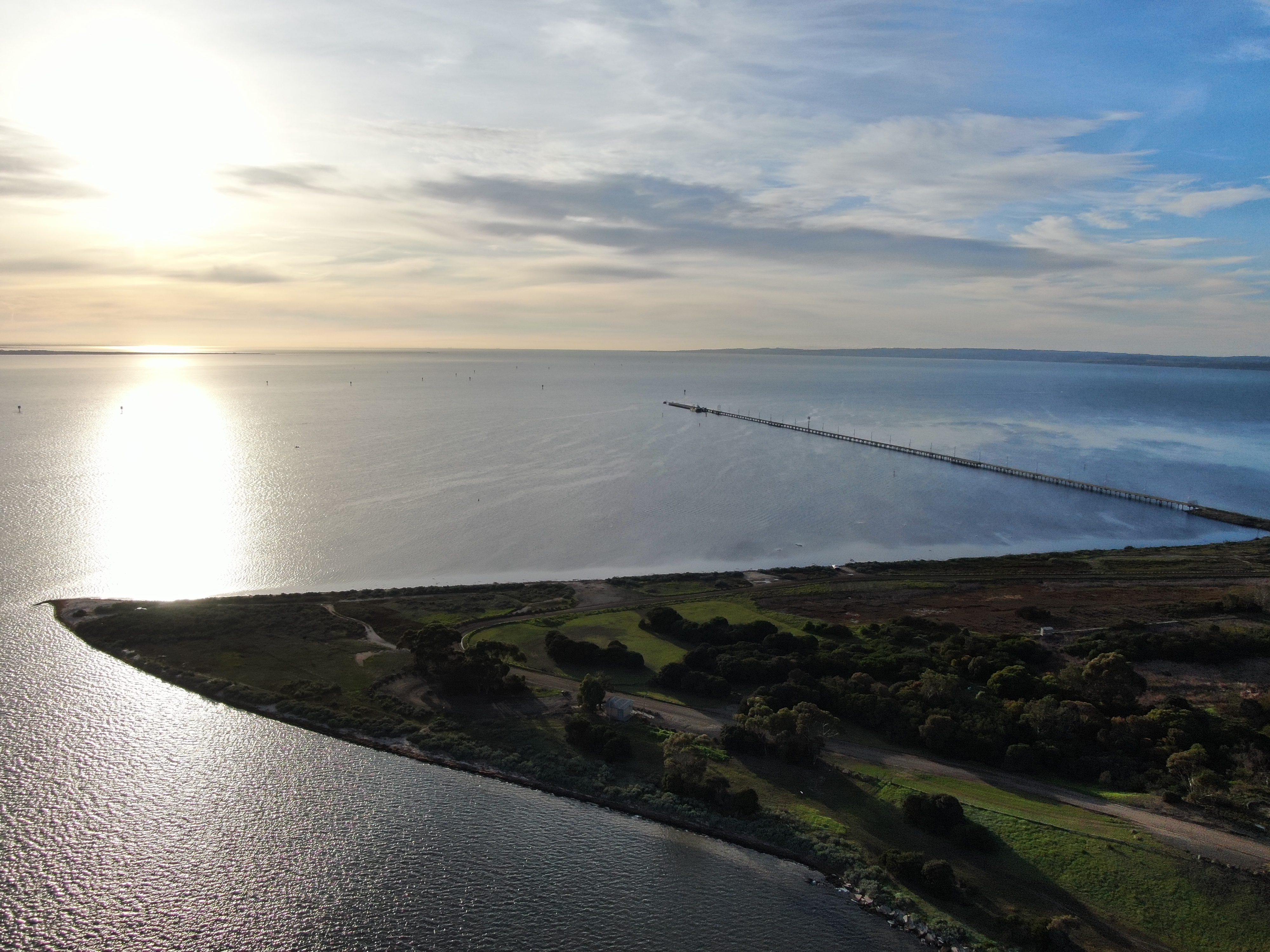 Image of a sunrise across Corio Bay, featuring a jetty and point of land